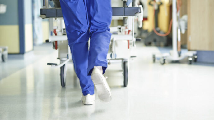Legs of medic running with gurney along hospital corridor