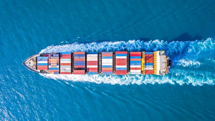overhead shot as cargo ship sails on a blue sea.