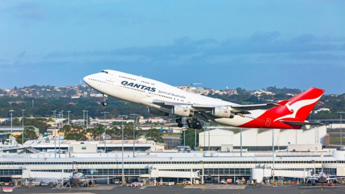 a Qantas 747 taking off from Sydney airport with the terminal building in the background.